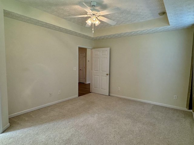 carpeted spare room with ceiling fan, a raised ceiling, and a textured ceiling