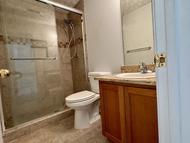 bathroom with vanity, toilet, an enclosed shower, and a textured ceiling