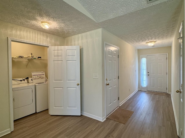 laundry room featuring hardwood / wood-style flooring, washing machine and dryer, and a textured ceiling