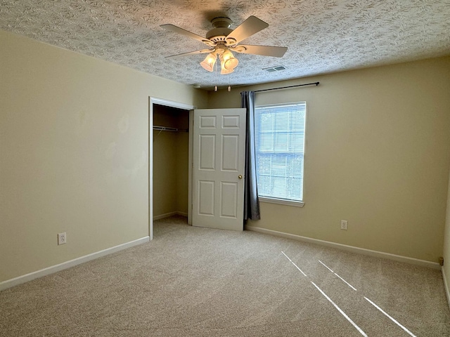 unfurnished bedroom with ceiling fan, carpet, a textured ceiling, and a closet