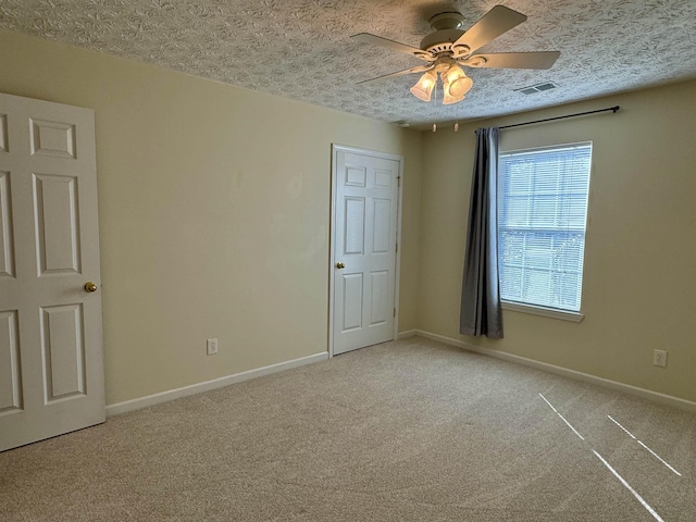 unfurnished room with ceiling fan, light colored carpet, and a textured ceiling