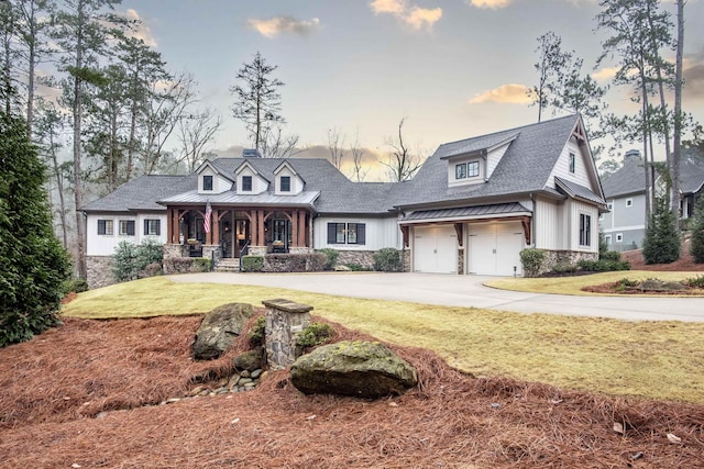 view of front of house with a porch, a garage, and a lawn