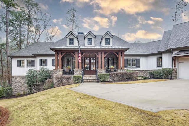 view of front of house with a garage, a front yard, french doors, and covered porch