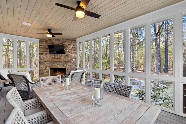 sunroom / solarium featuring a fireplace, wood ceiling, and a ceiling fan