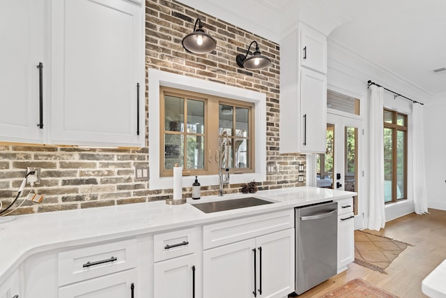 kitchen featuring a sink, stainless steel dishwasher, light wood-style floors, white cabinets, and light countertops