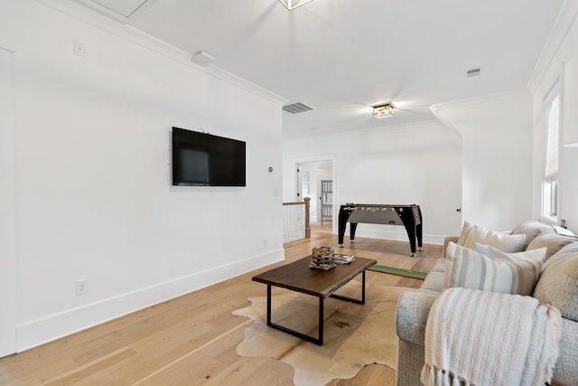 living room featuring visible vents, baseboards, crown molding, and light wood-style floors