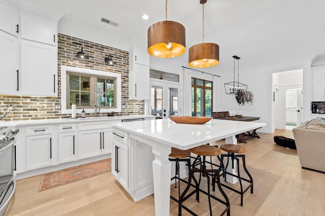 kitchen with visible vents, backsplash, a kitchen island, crown molding, and light countertops