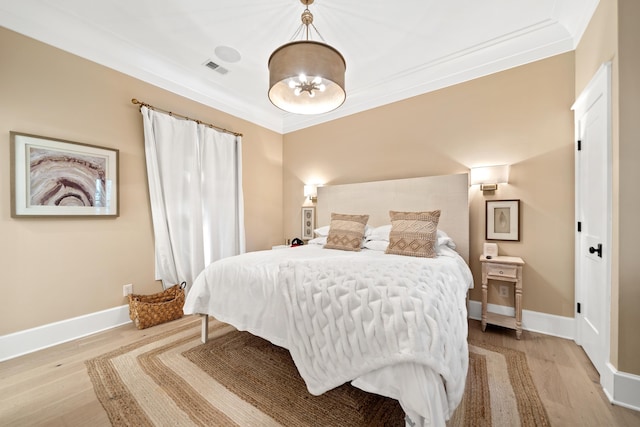 bedroom featuring visible vents, baseboards, ornamental molding, light wood-style flooring, and an inviting chandelier