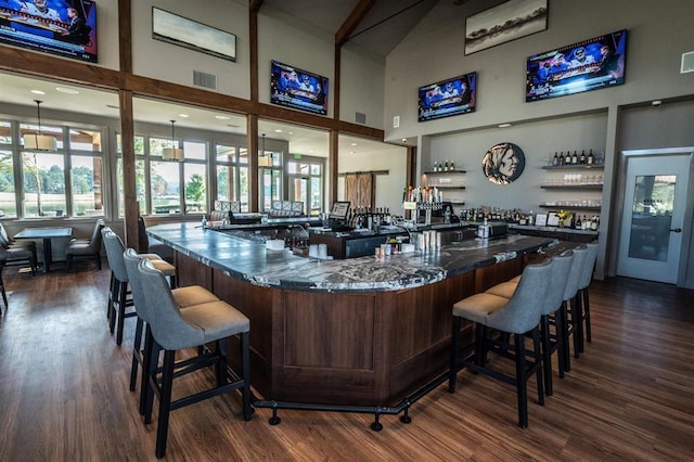 bar featuring dark wood-style floors, visible vents, a dry bar, and a high ceiling