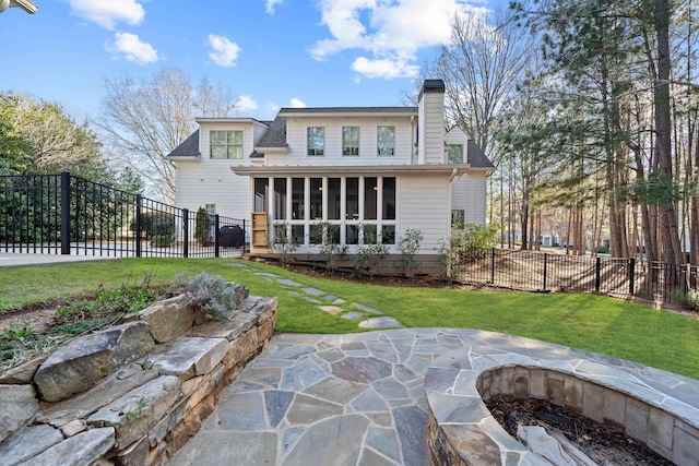 rear view of house featuring a patio, fence, a lawn, and a sunroom