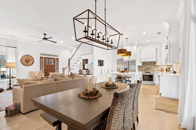 dining room with light wood finished floors, visible vents, crown molding, stairway, and recessed lighting