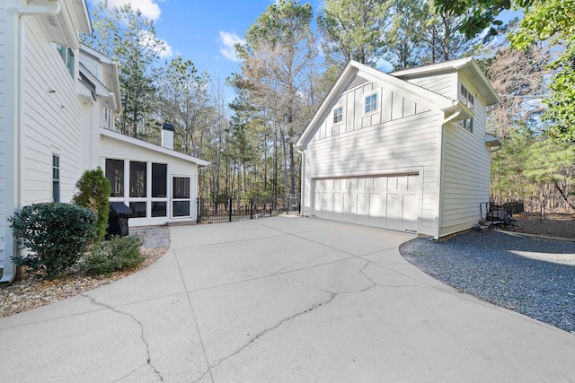 view of home's exterior with board and batten siding, a garage, and fence