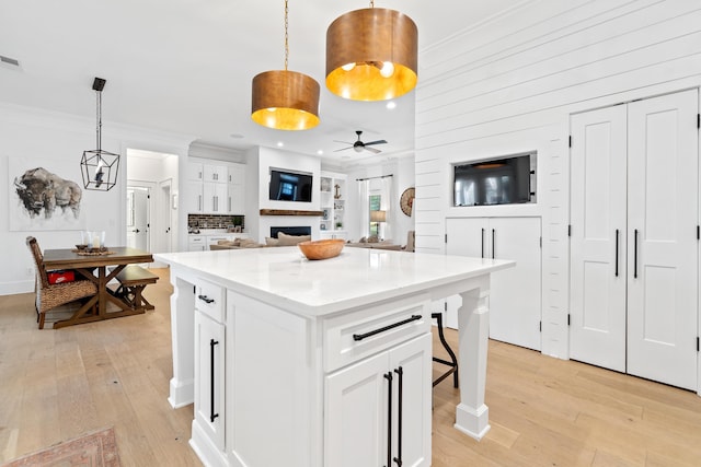 kitchen with light wood-style flooring, ornamental molding, a center island, and white cabinetry