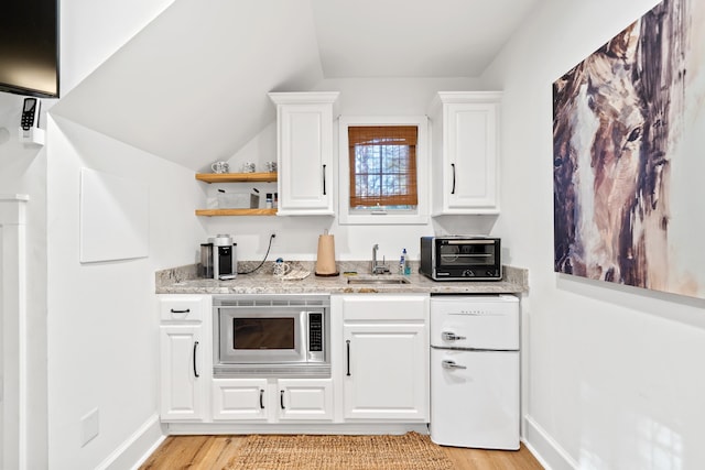 kitchen featuring a toaster, a sink, white cabinetry, stainless steel microwave, and light wood-type flooring