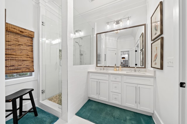 full bathroom with a shower stall, crown molding, double vanity, and a sink