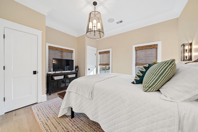 bedroom with a notable chandelier, visible vents, light wood-type flooring, and crown molding