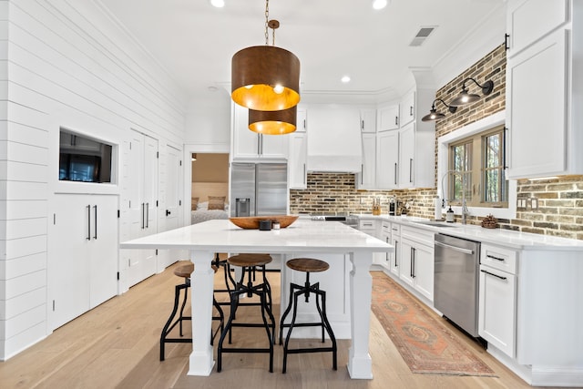 kitchen featuring visible vents, ornamental molding, appliances with stainless steel finishes, custom exhaust hood, and a sink