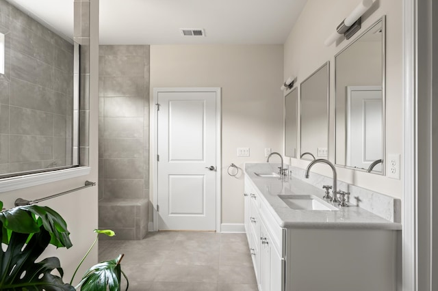 full bath featuring double vanity, walk in shower, visible vents, and a sink