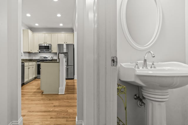 775 Markhams Dr, Madison, GA 30650 - kitchen with stainless steel appliances, ornamental molding, dark countertops, light wood finished floors, and tasteful backsplash