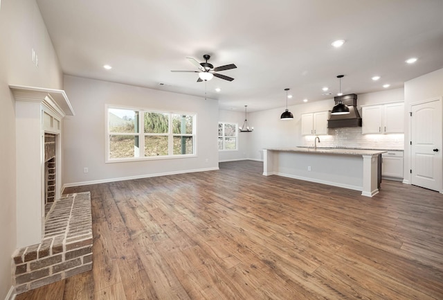 unfurnished living room with ceiling fan with notable chandelier, sink, and hardwood / wood-style floors