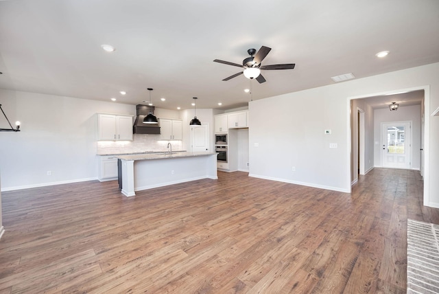 unfurnished living room with ceiling fan, sink, and hardwood / wood-style floors