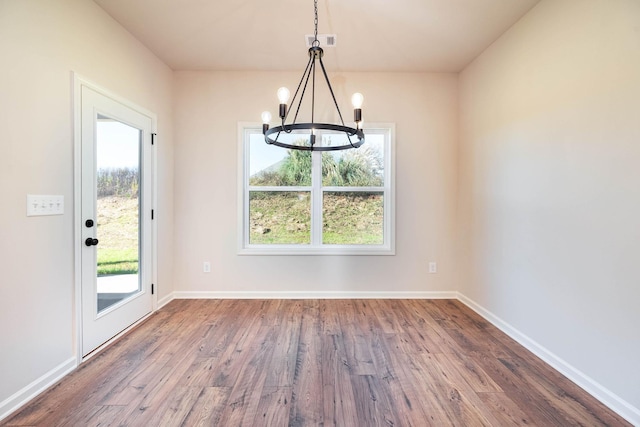 unfurnished dining area with hardwood / wood-style flooring and a chandelier