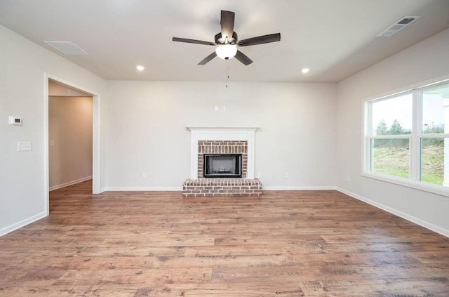 unfurnished living room with ceiling fan, a fireplace, and hardwood / wood-style floors