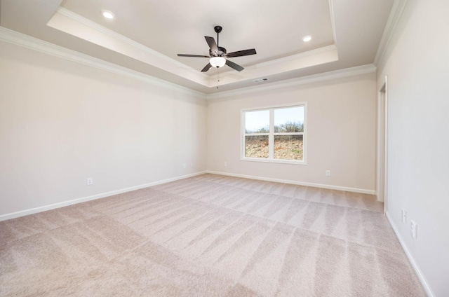 carpeted spare room with crown molding, a tray ceiling, and ceiling fan