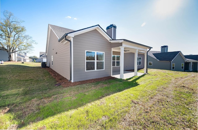 rear view of property with ceiling fan, a patio area, and a lawn