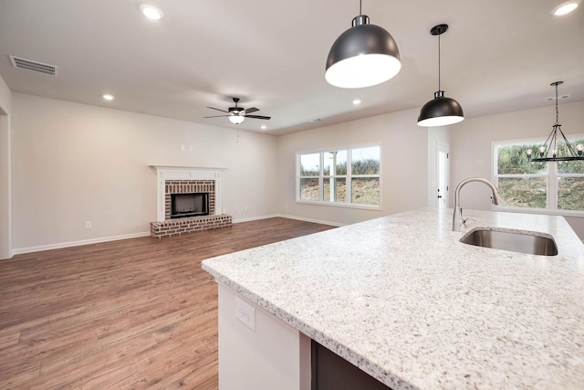 kitchen with light stone countertops, sink, pendant lighting, and plenty of natural light