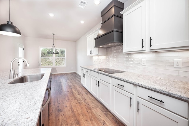 kitchen with custom exhaust hood, light stone countertops, sink, and white cabinets