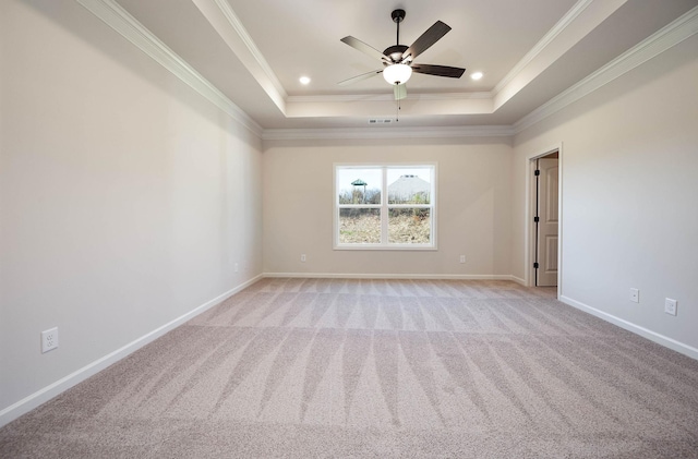 empty room featuring ceiling fan, light colored carpet, ornamental molding, and a tray ceiling