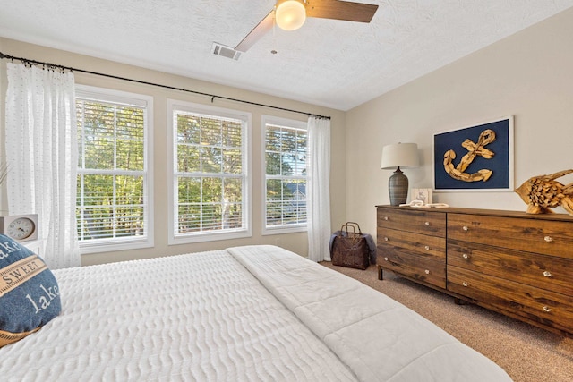 bedroom with carpet floors, ceiling fan, visible vents, and a textured ceiling