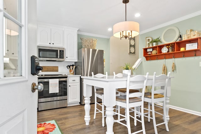 kitchen with appliances with stainless steel finishes, dark wood finished floors, white cabinetry, and crown molding