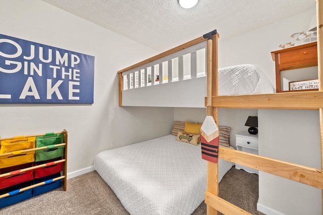 carpeted bedroom featuring a textured ceiling and baseboards