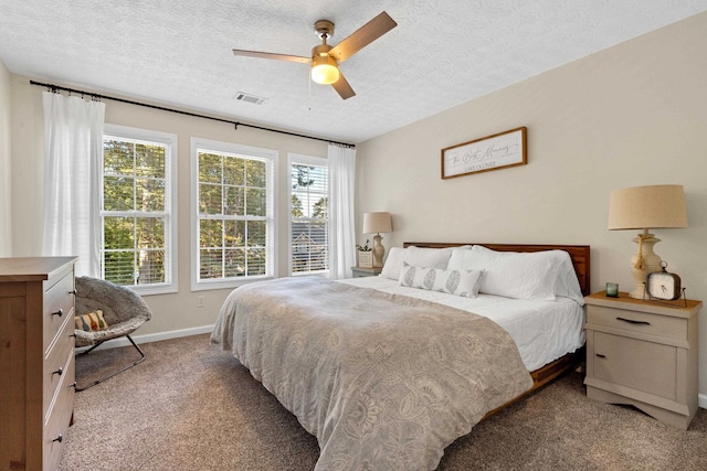 carpeted bedroom with a textured ceiling, a ceiling fan, visible vents, and baseboards