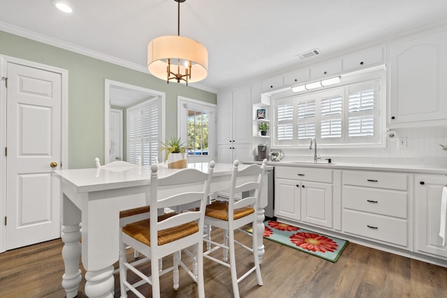 kitchen featuring visible vents, dark wood-style floors, ornamental molding, white cabinetry, and a sink