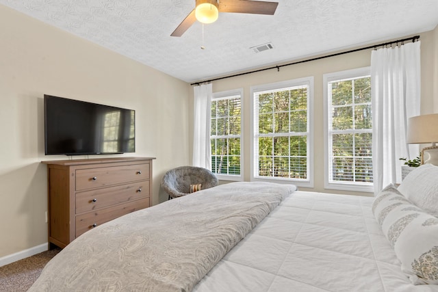 carpeted bedroom featuring baseboards, visible vents, ceiling fan, and a textured ceiling