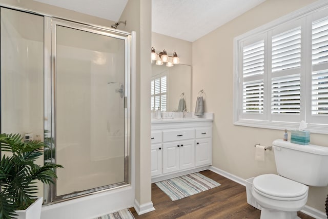 full bathroom featuring toilet, wood finished floors, vanity, baseboards, and a shower stall