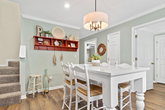 dining space with baseboards, ceiling fan, stairway, wood finished floors, and crown molding