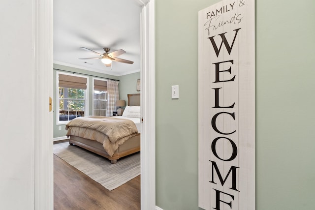 bedroom featuring wood finished floors, a ceiling fan, baseboards, access to outside, and crown molding