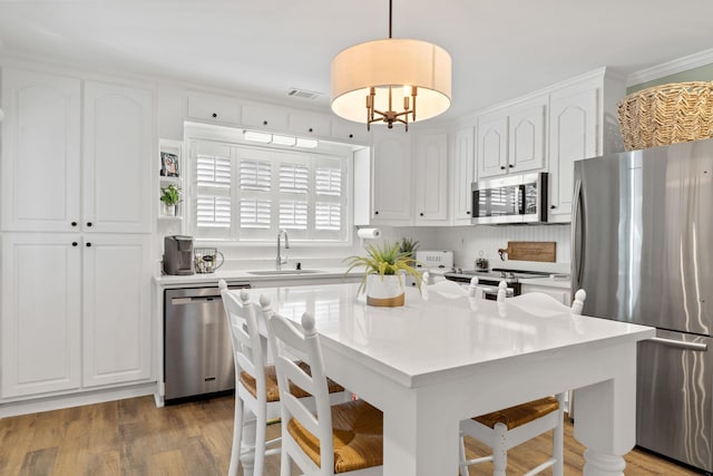 kitchen with visible vents, white cabinets, appliances with stainless steel finishes, a breakfast bar, and a sink