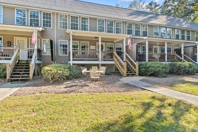 townhome / multi-family property with roof with shingles, stairs, a porch, and a front yard