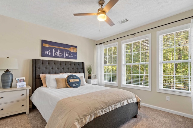 bedroom featuring a textured ceiling, multiple windows, carpet flooring, and visible vents