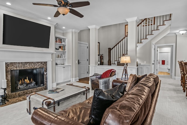 living room featuring light colored carpet, a high end fireplace, ornamental molding, and ceiling fan