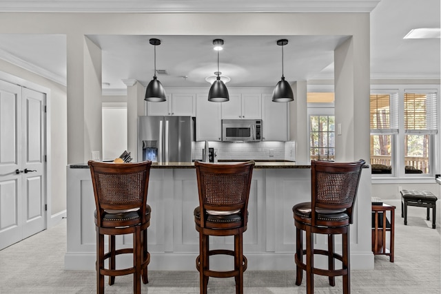 kitchen with appliances with stainless steel finishes, dark stone countertops, white cabinets, and decorative light fixtures