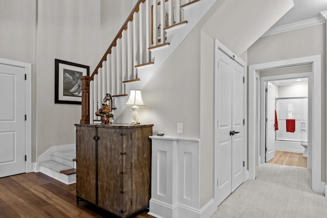 stairs with hardwood / wood-style flooring and crown molding