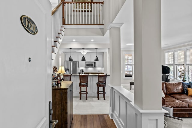 interior space featuring a high ceiling, ornate columns, and light hardwood / wood-style flooring