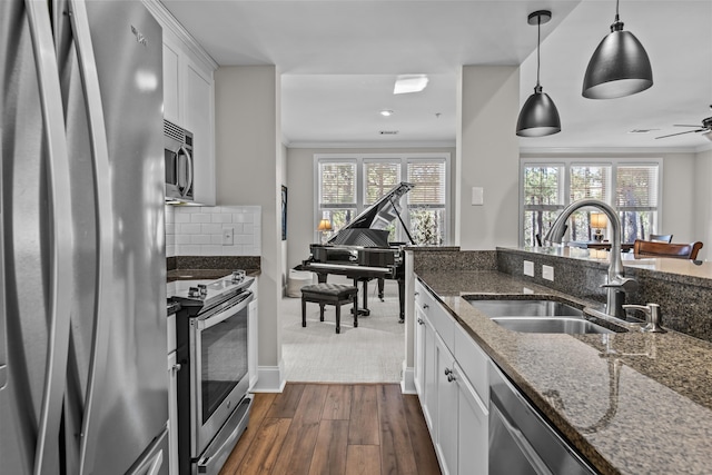 kitchen featuring pendant lighting, sink, stainless steel appliances, white cabinets, and dark stone counters