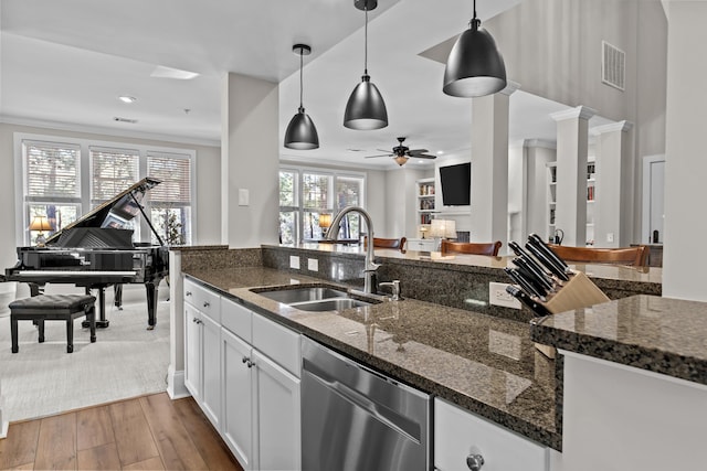 kitchen with sink, white cabinetry, hanging light fixtures, dishwasher, and dark stone counters